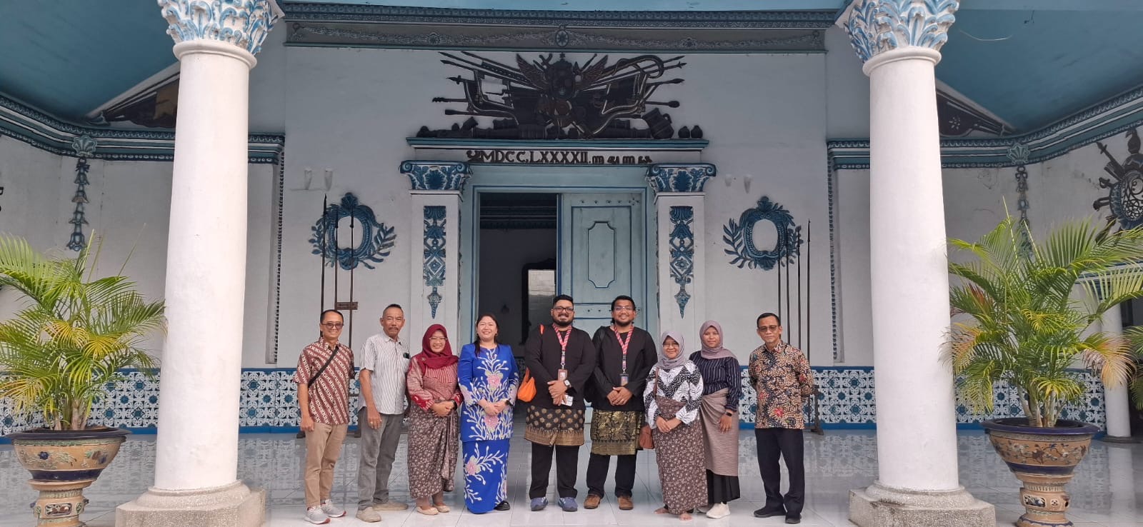 Fitri and colleagues posing together outside a historic building in Indonesia