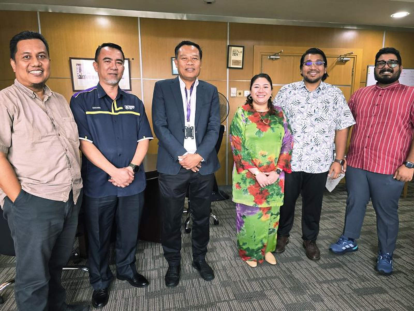 Fitri Salim standing with five academic colleagues indoors.